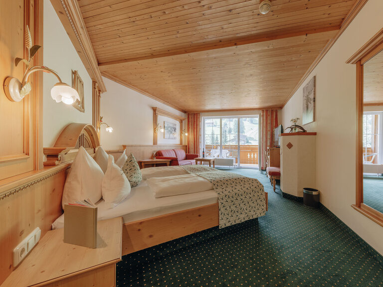 Ein helles Schlafzimmer mit elegantem Bett und großen Spiegel, der die Raumgröße des Superior-Zimmers hervorhebt.