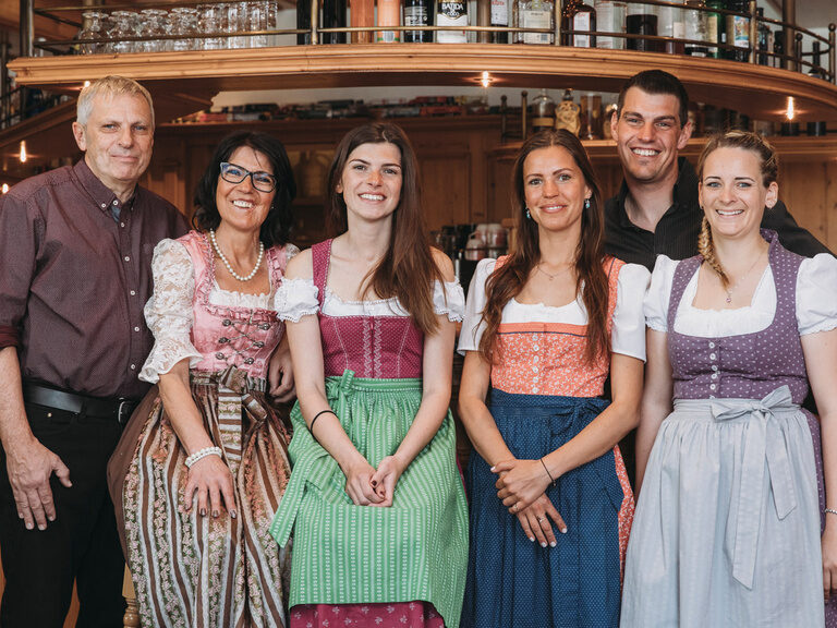 Die Gastgeberfamilie des Hotels Hirschen steht vor der Bar und lächelt in die Kamera.