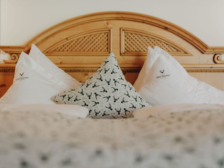 Das große hölzerne Bett im im Superior-Zimmer im Hotel Hirschen bei Montafon bietet genug Platz für erholsame Stunden.