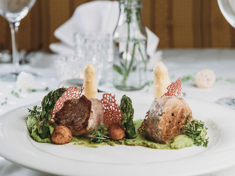 Auf einem weißen Porzellan Teller wurde ein kunstvolles Gericht mit Pilzen und Fleisch serviert.