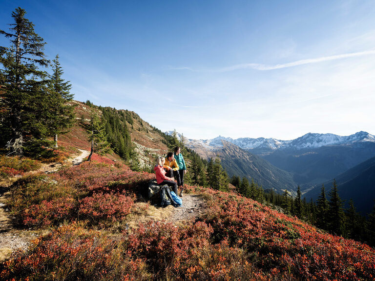 Eine Gruppe Wanderer ruht auf einer Bank mit Blick auf das atemberaubende Hochgebirgsland im Montafon.