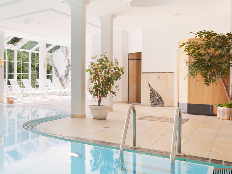 Der große Pool im Hotel Hirschen mach eine Biegung und endet neben den Liegen.